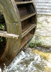 image of limited water-wheel against stone-wall with water below